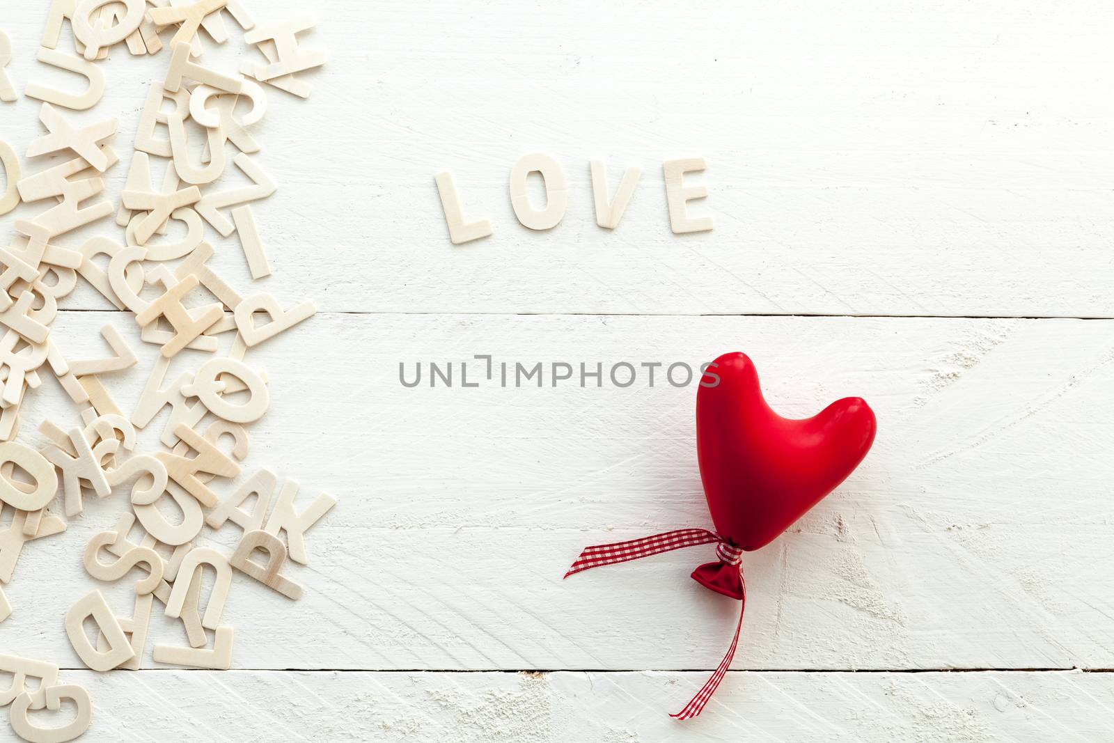 Love and red heart with a bow on white background and scattered letters view from above