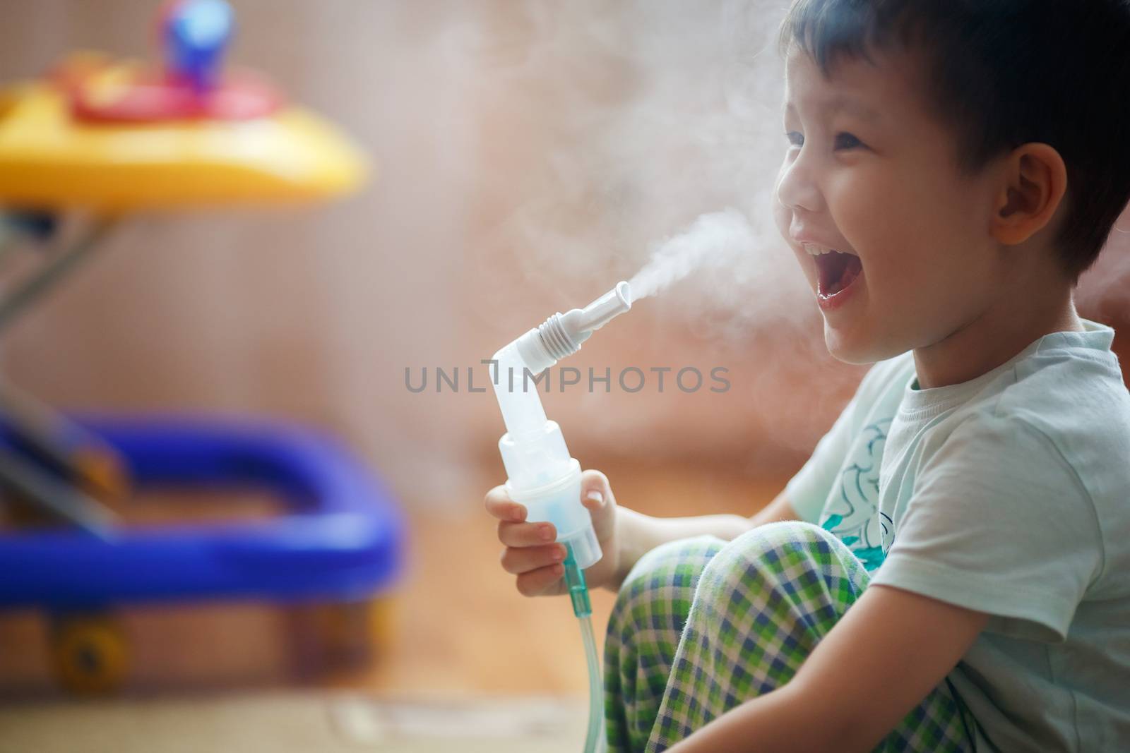 Little boy makes inhalation at home, taking medication to the bronchial tubes. Exhales steam through the tube.