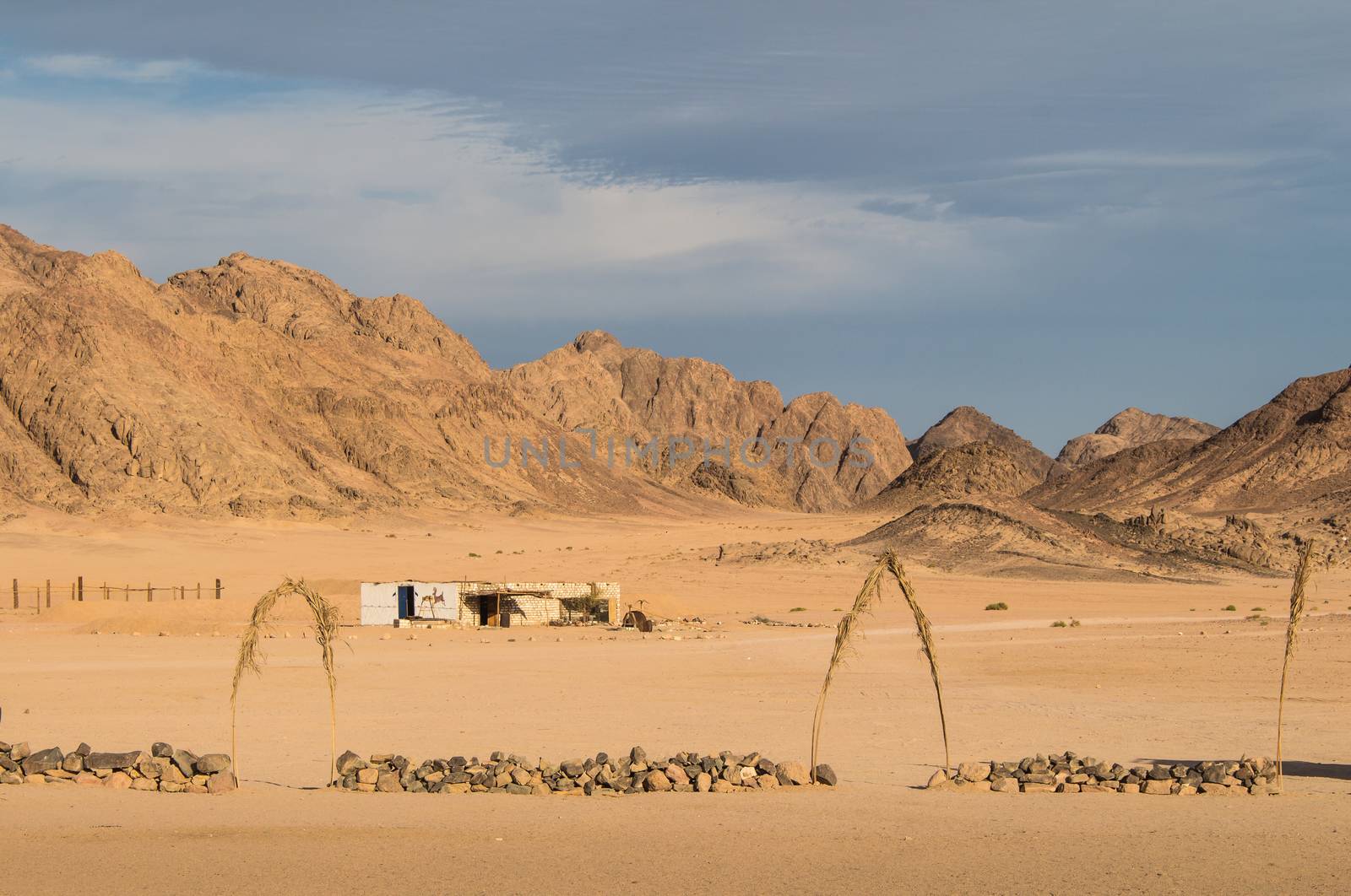 Bedouin village in the desert in Egypt. Plane terrain and high mountains. Cloudy early evening sky.