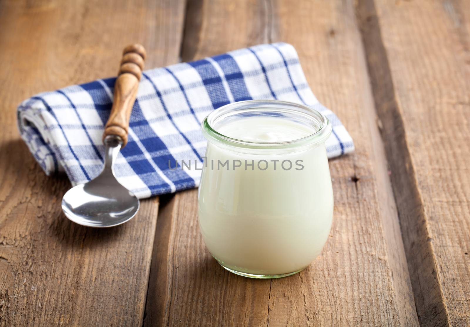 Delicious, nutritious and healthy yogurt in a glass jars with spoon on wooden background