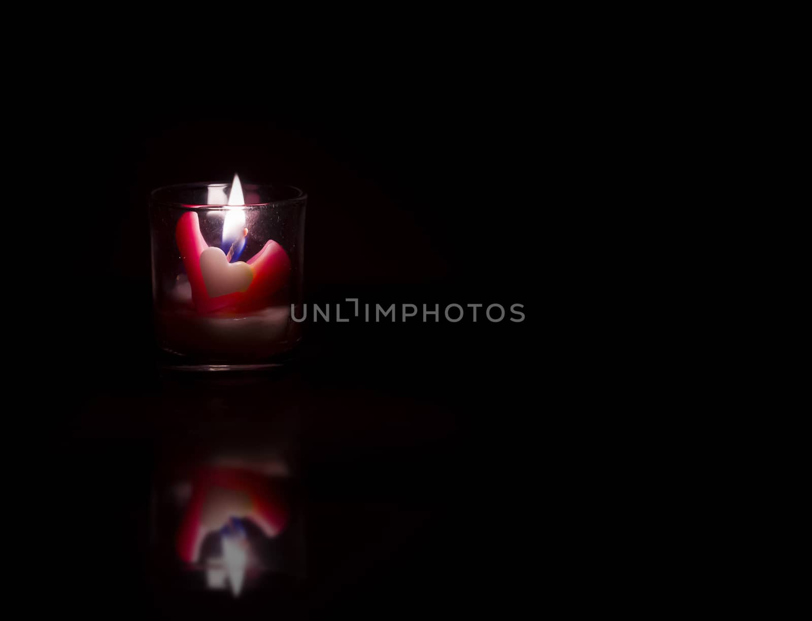 Heart shaped candles on black background by anatskwong
