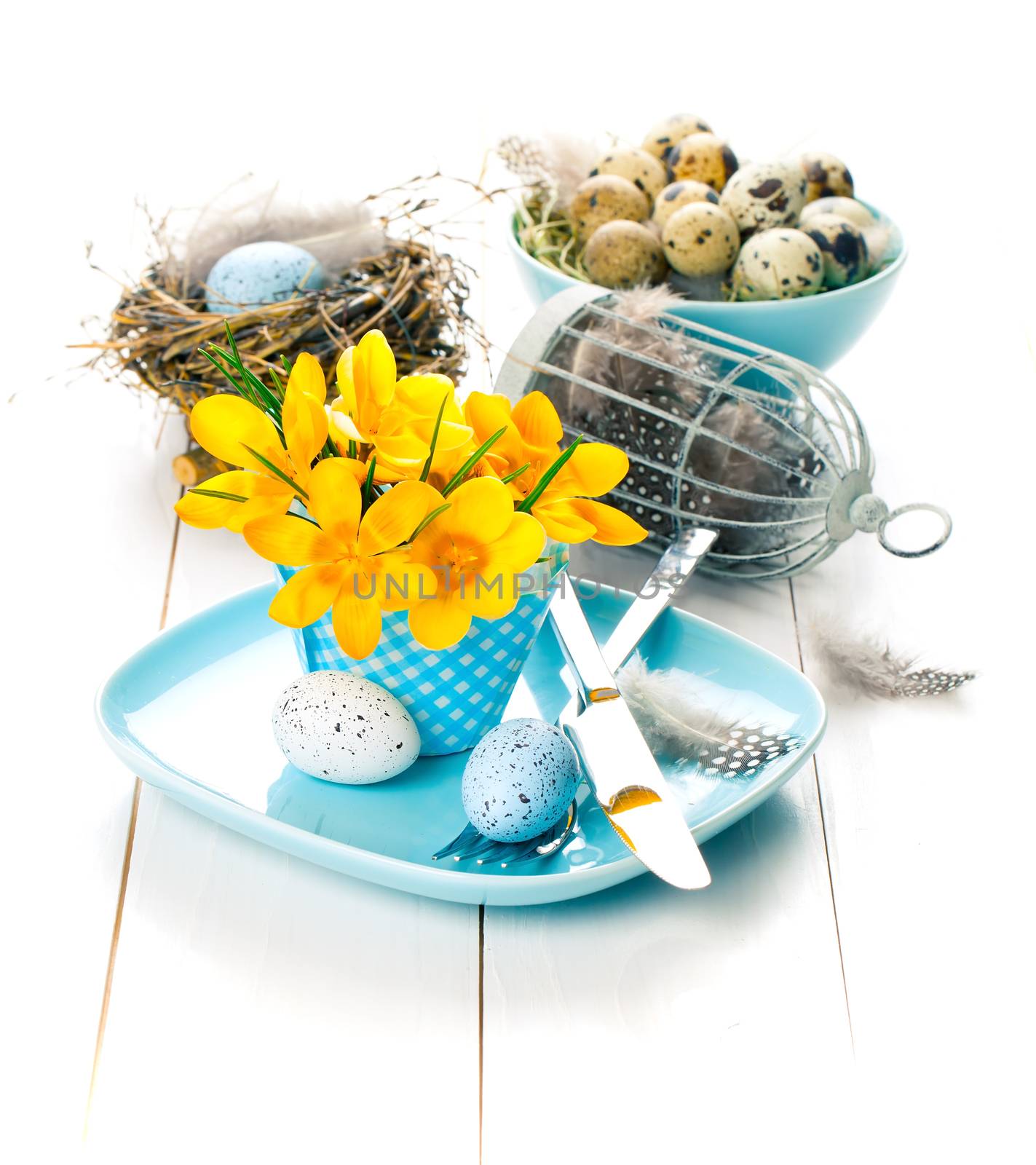 table decoration with easter eggs nest on plate, on white wooden background