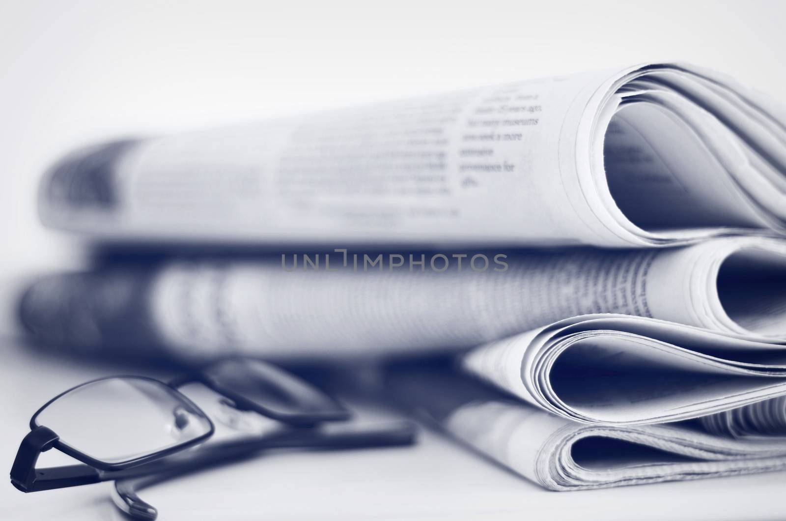 A stack of newspapers with glasses. Shallow depth of field.