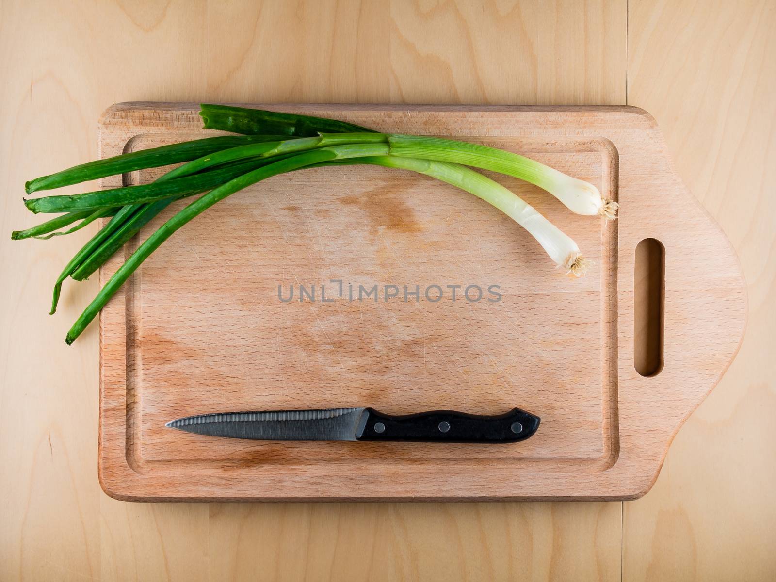 Bunch onion on wooden board with knife, copyspace by weruskak