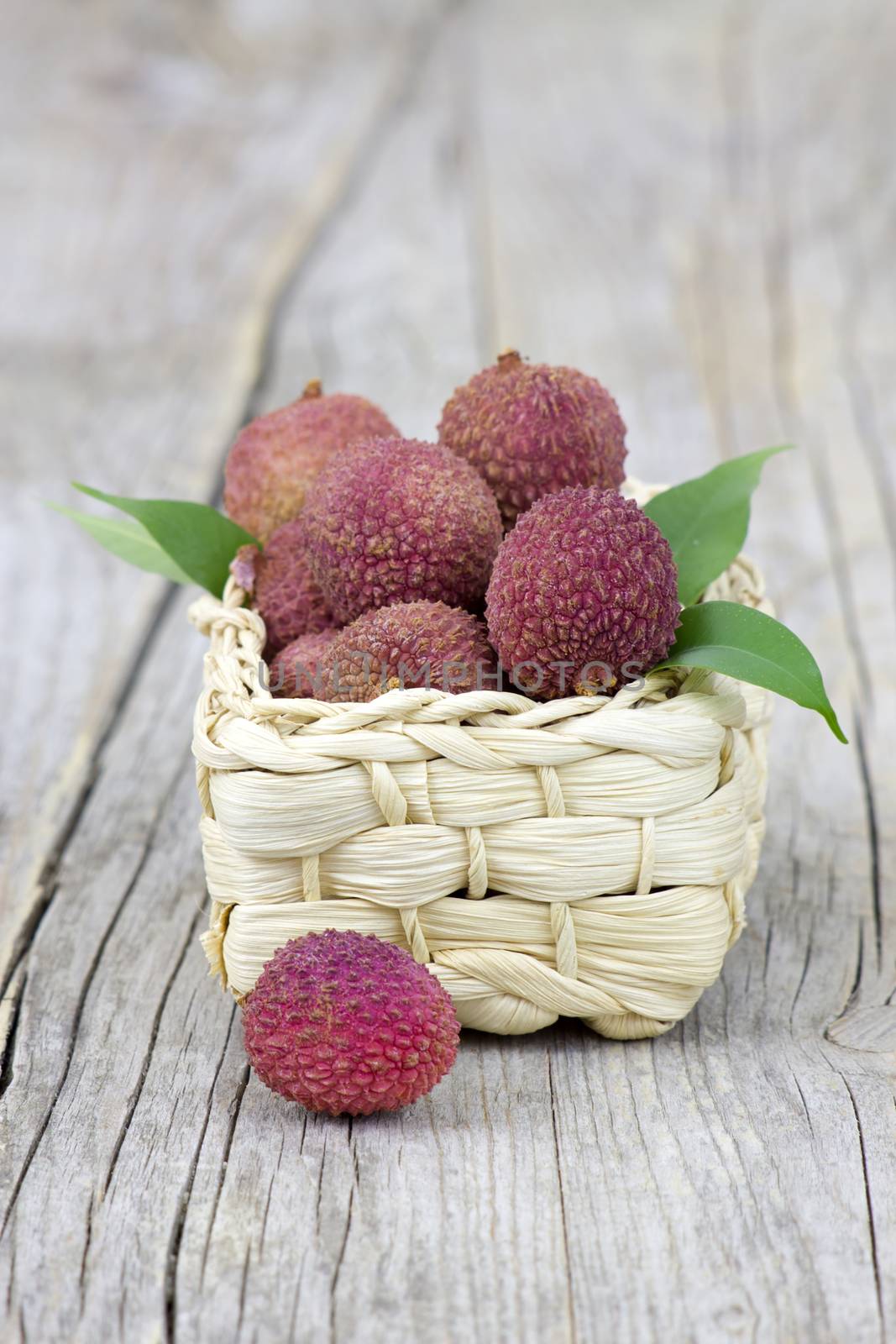 fresh lychees in a basket on wooden background