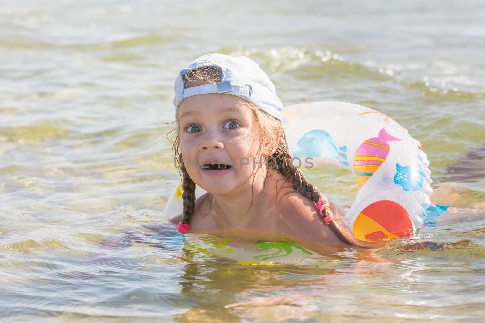 Four-year girl swims in the water with wearing the swimming circle