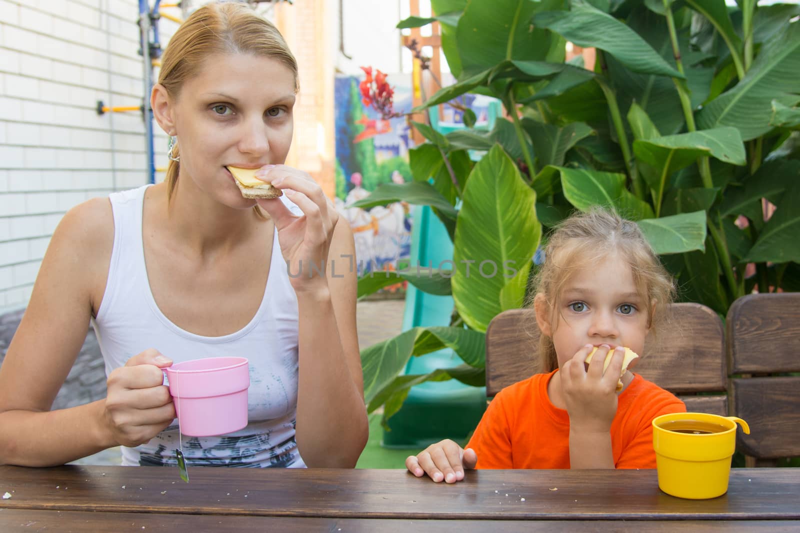 pretty young mother and five year old daughter having breakfast on the veranda