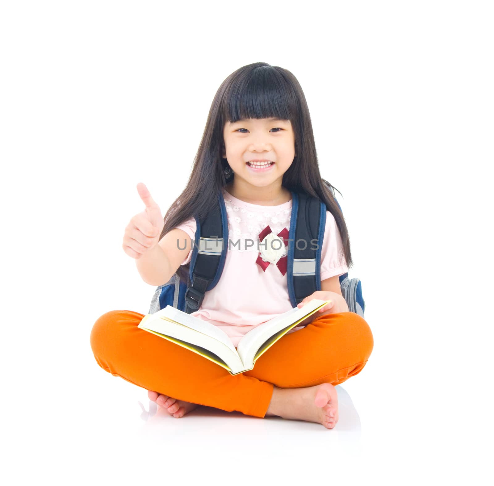 Asian girl sitting on the floor and reading. Isolated on white background.