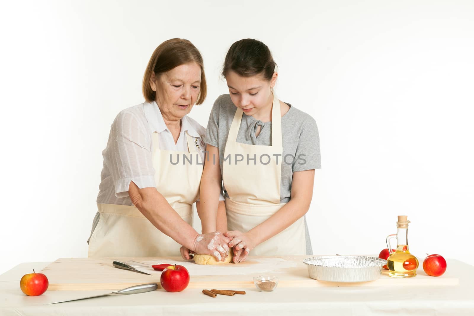 the grandmother and the granddaughter knead dough on a kitchen table