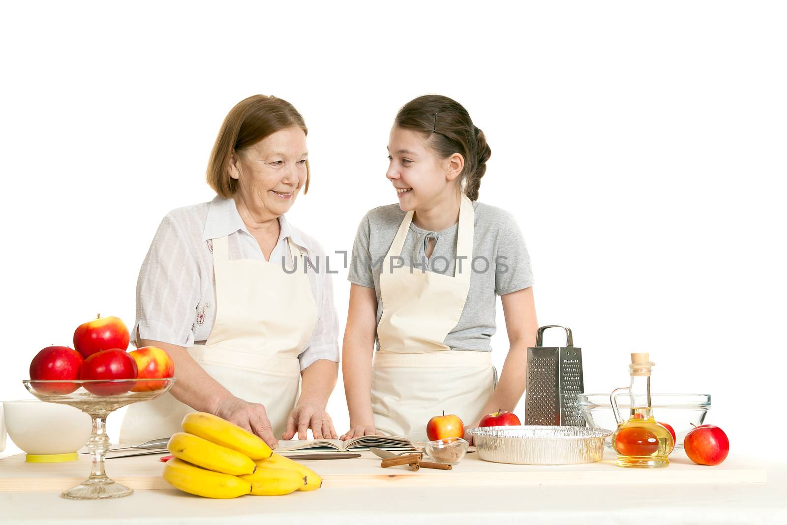 the grandmother and the granddaughter read the recipe-book before cooking of food and smile each other