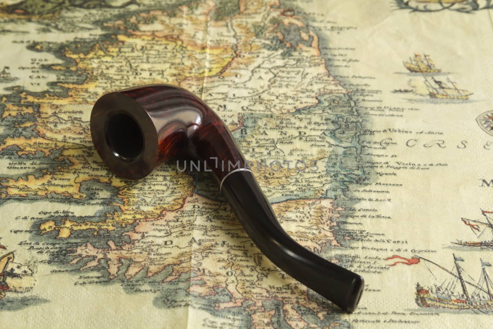 tobacco pipe lying on the ancient map of treasures