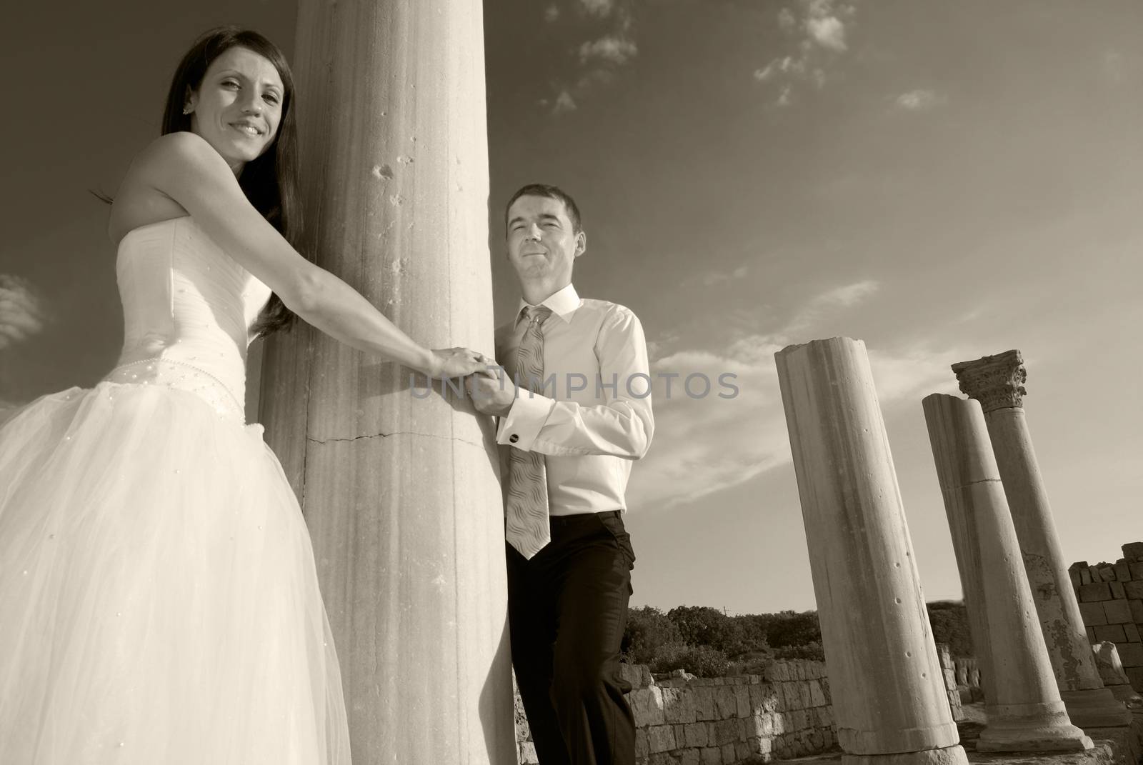 Beautiful wedding couple- bride and groom near greece column in the ancient city. Black and white, sepia