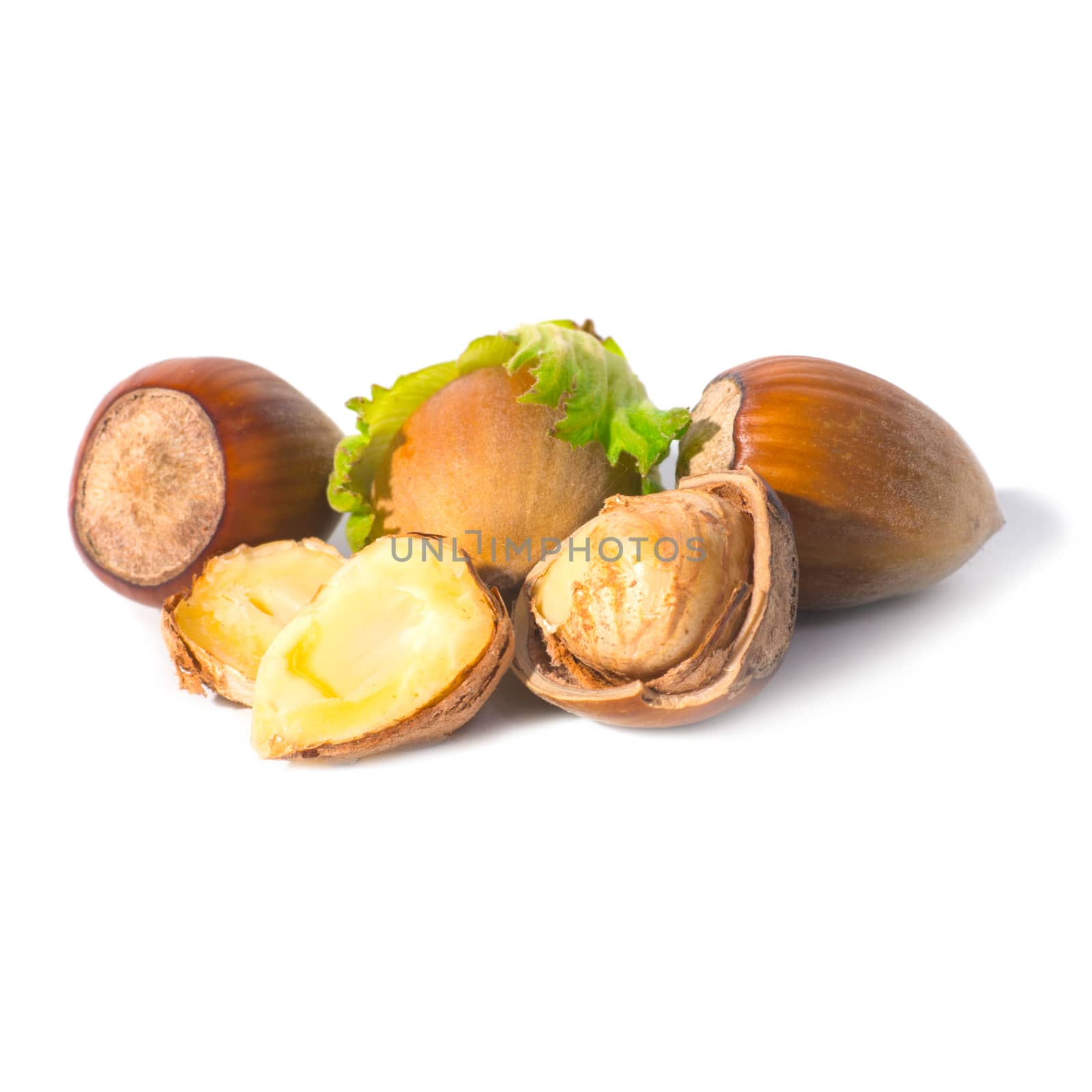 Pile of filbert nuts with green leaf isolated on white