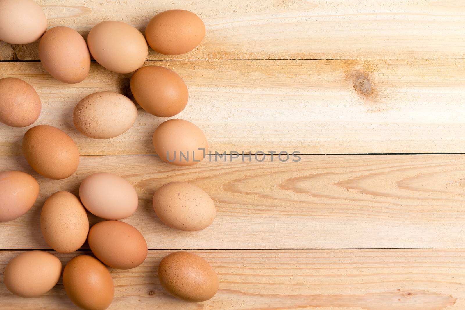 Batch of farm fresh brown eggs displayed as a layer on a wooden table with copy space viewed from above in a healthy diet concept