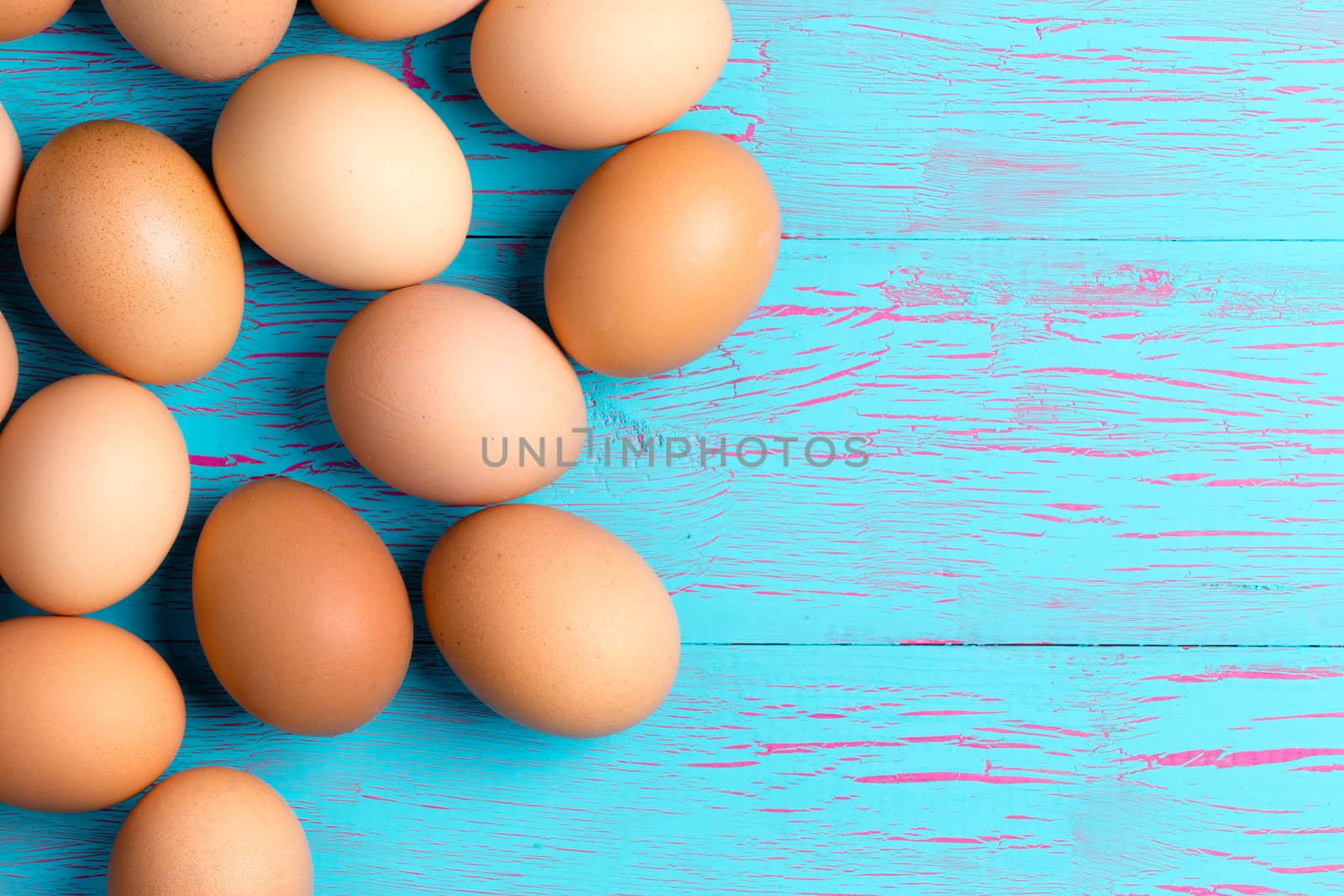 Fresh healthy brown eggs for breakfast on a crackle painted tropical blue table with copyspace, overhead view in a healthy diet and nutrition concept