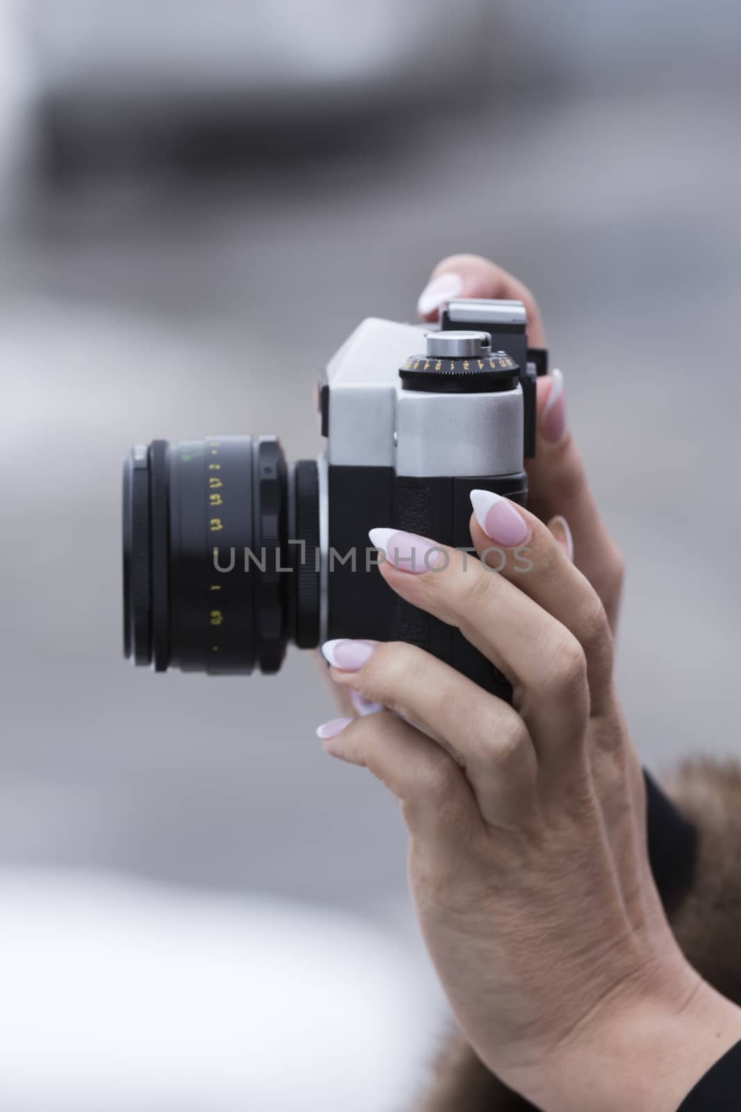 girl with a nice manicure holding vintage camera in the hands of