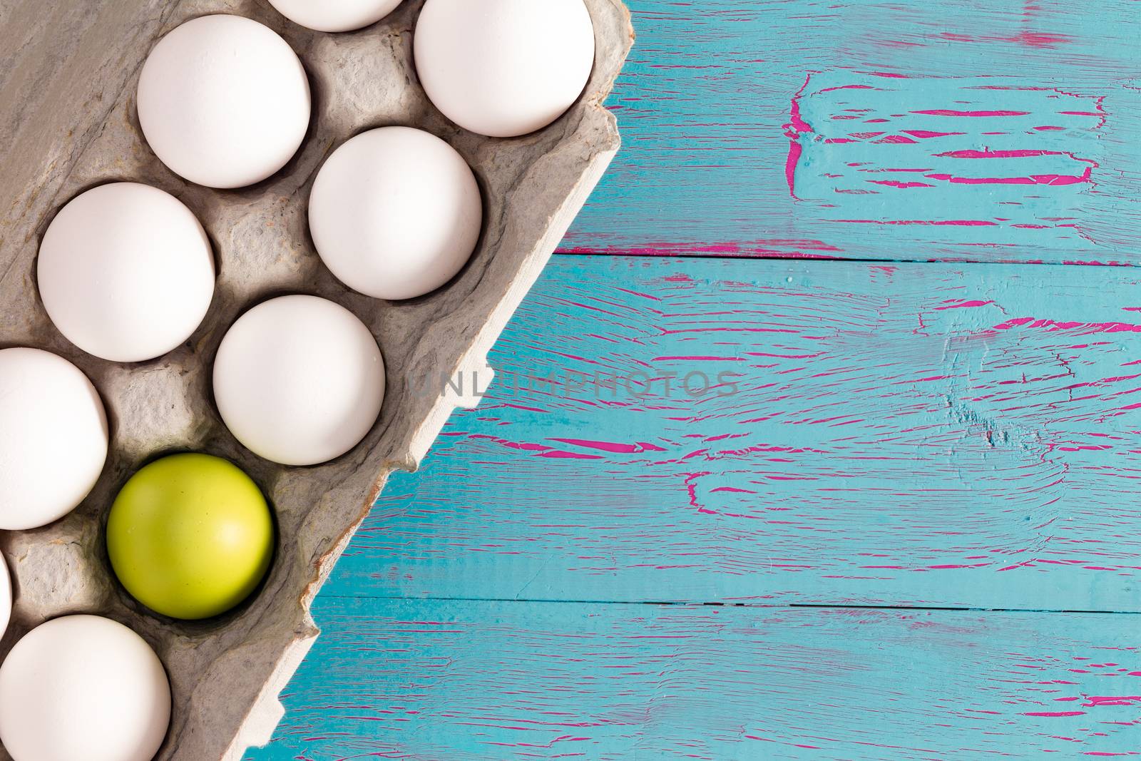 Egg box of white Easter eggs with one green one by coskun