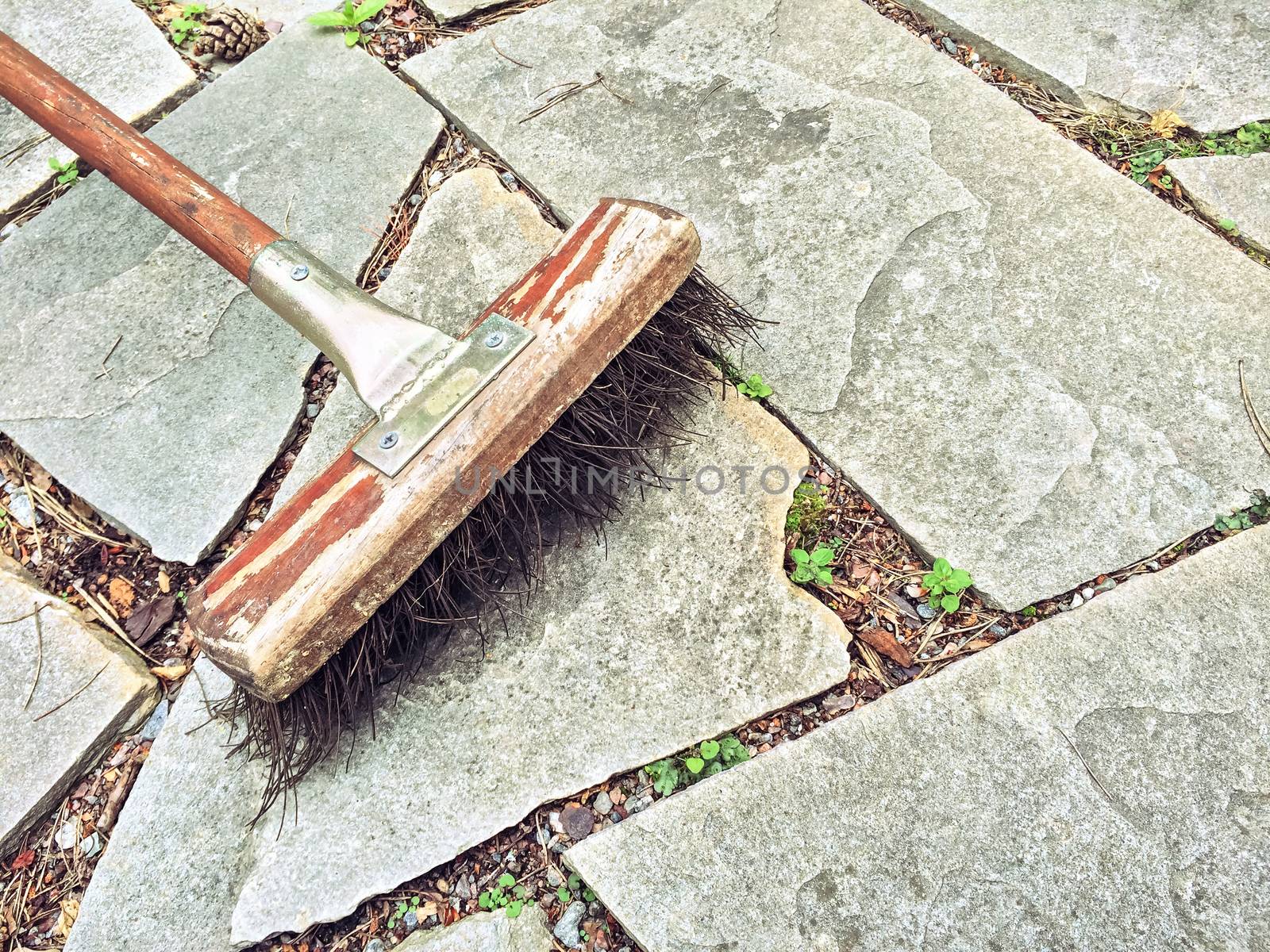 Rustic style broom on stone path in the garden.