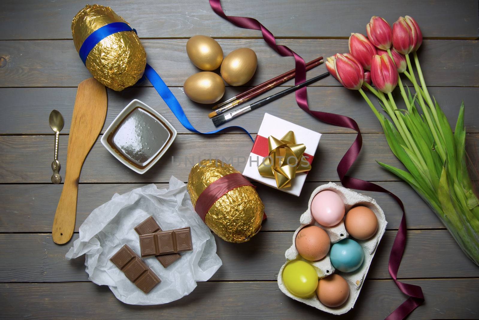 Gold easter eggs with spring tulips and gift box on a wooden table