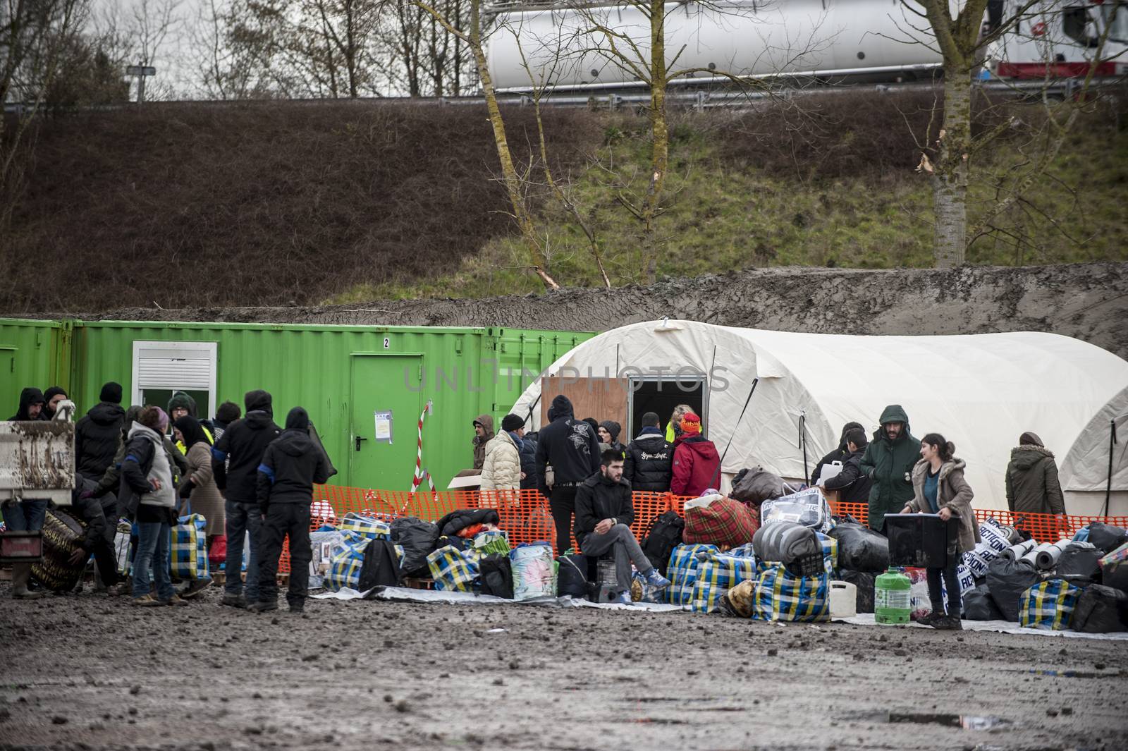 FRANCE, Grande-Synthe: Migrants gather outside tents at the new camp at Grande Synthe on March 7, 2016.The new camp features make shift shelters to provide more protection from the elements. Also available are better sanitation measures including showers and toilets.  