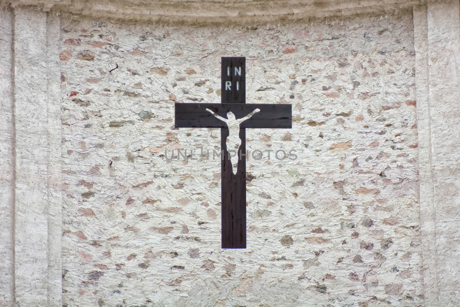 Black cross with Jesus hanging on the stone wall