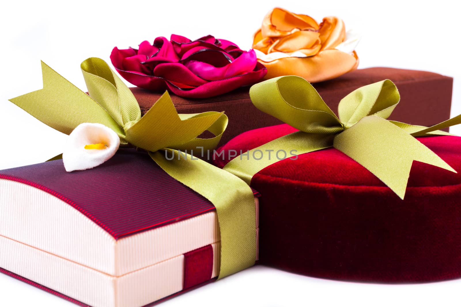 Luxury gift boxes in dark red and brown shades with green satin ribbon and bow isolated over white background.