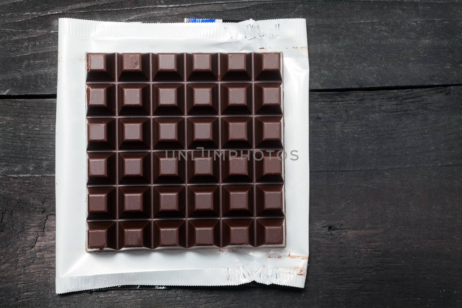Dark chocolate bar in opened foil wrapping