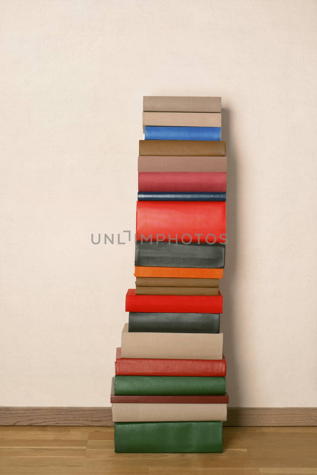 Old colorful books on wooden floor near the white wall