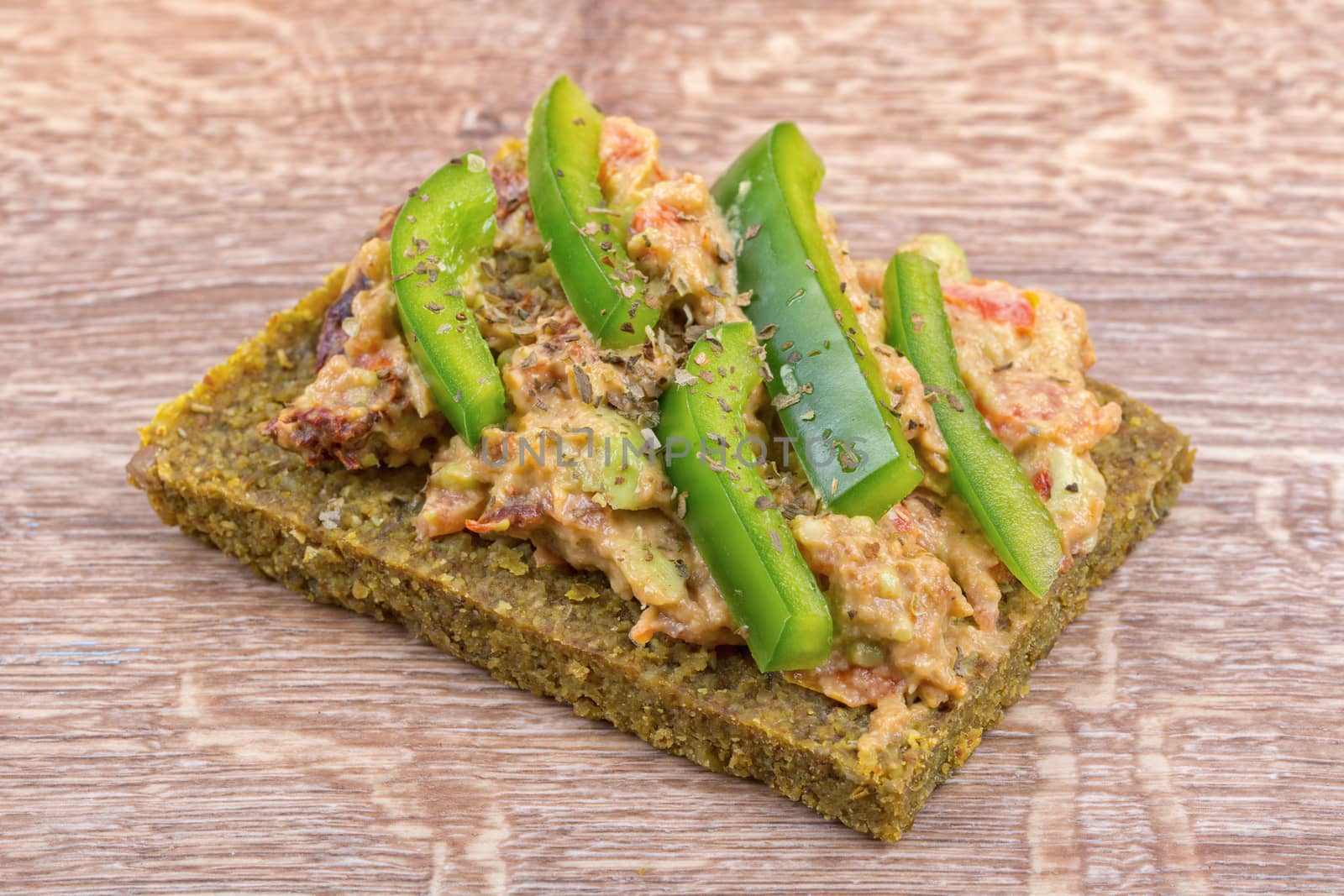 Raw bread with a spread decorated with green pepper