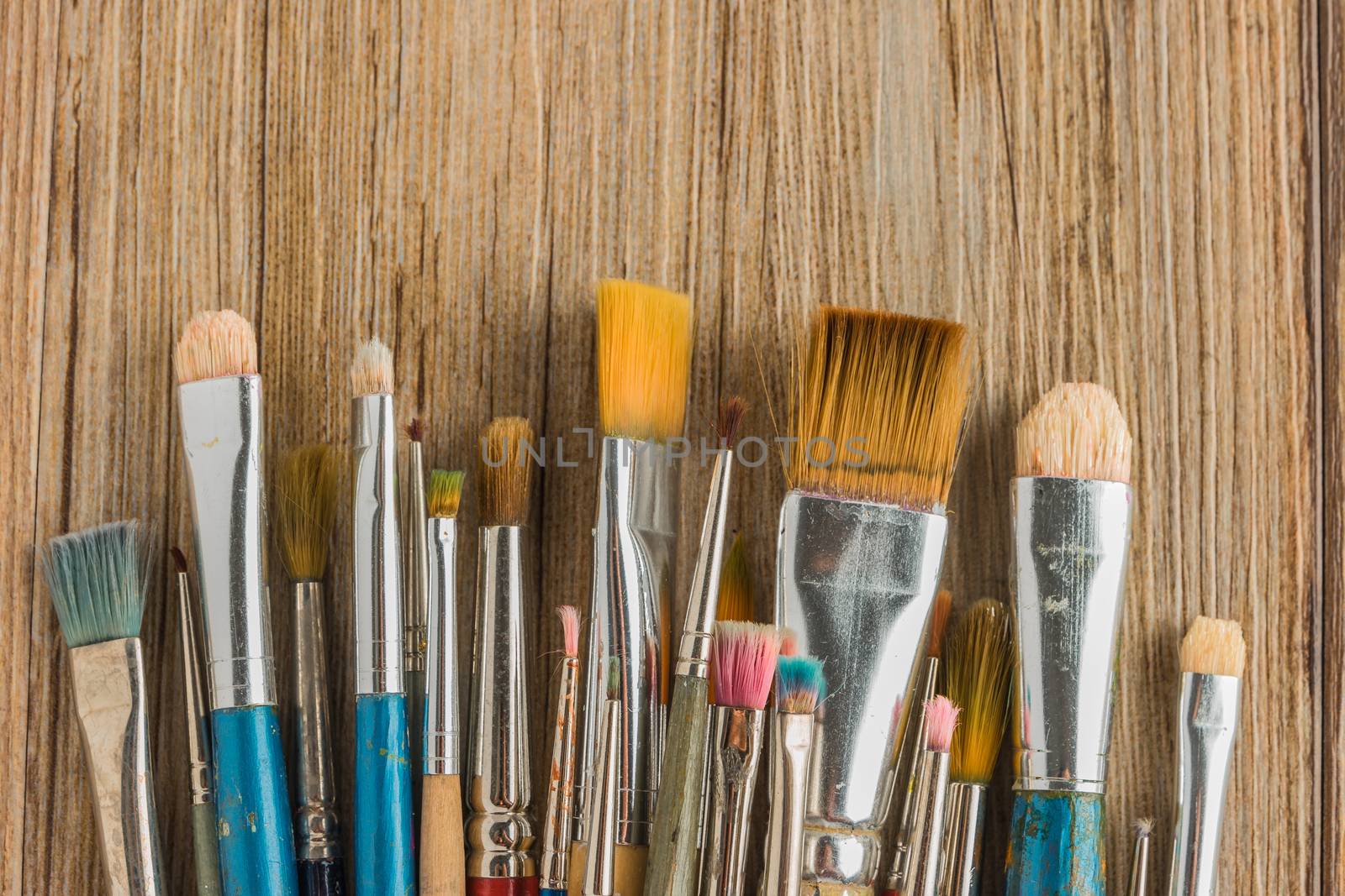 Artist paint brushes over rustic wooden texture by AnaMarques