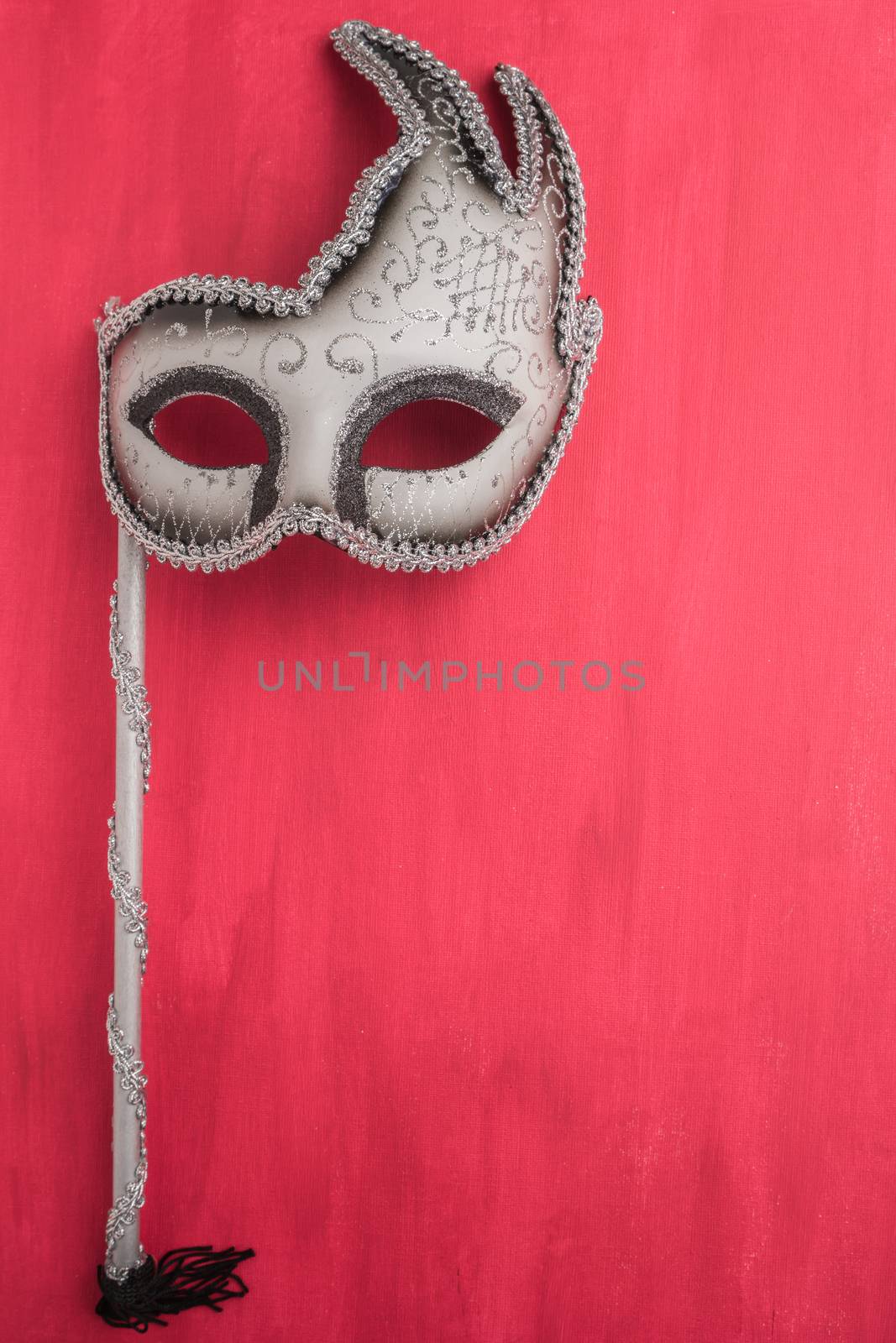 Colorful carnival mask on a red textured background. Masks with theater concept. Top view with copy space