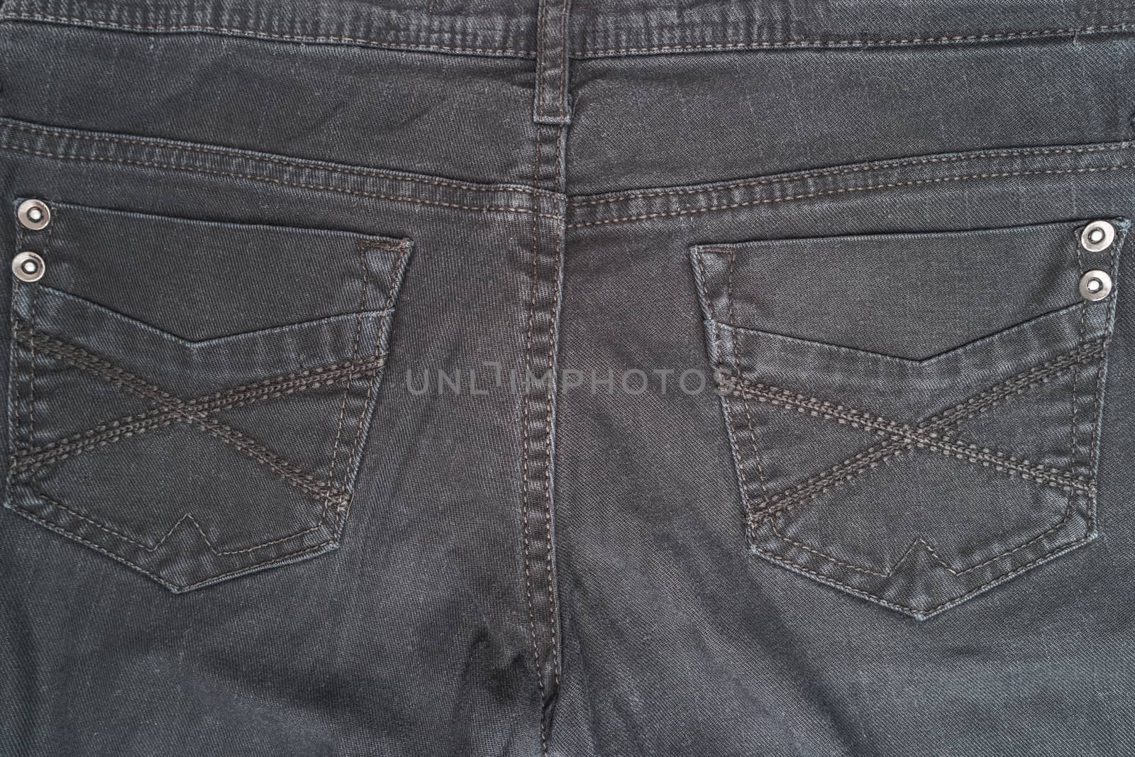 Closeup detail of black denim jeans trousers pocket, texture background. Top view with copy space