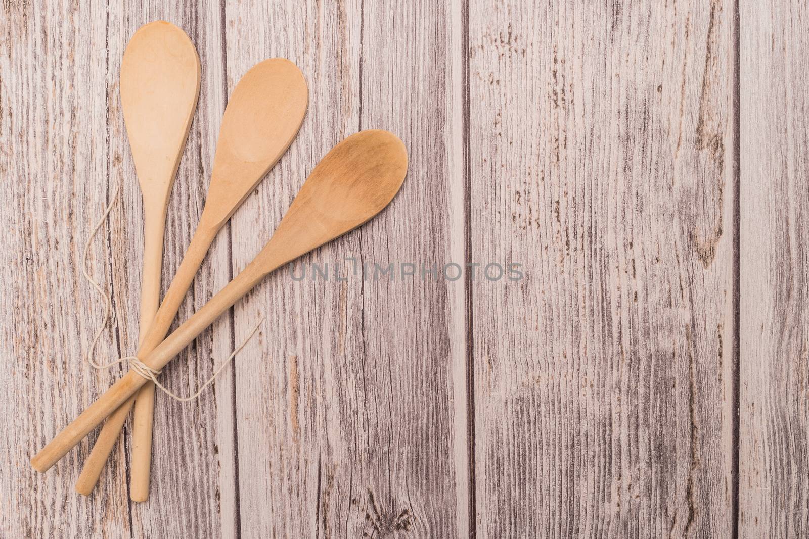 Wooden spoon tied up with a ribbon on rustic background by AnaMarques