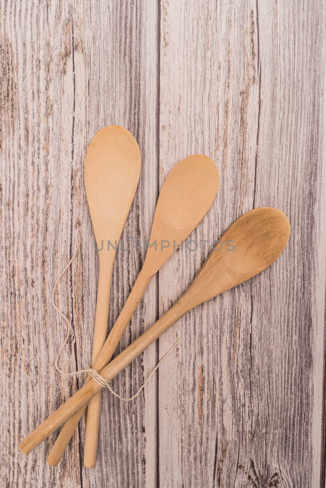 Wooden spoon tied up with a ribbon on rustic background. Top view with copy space.