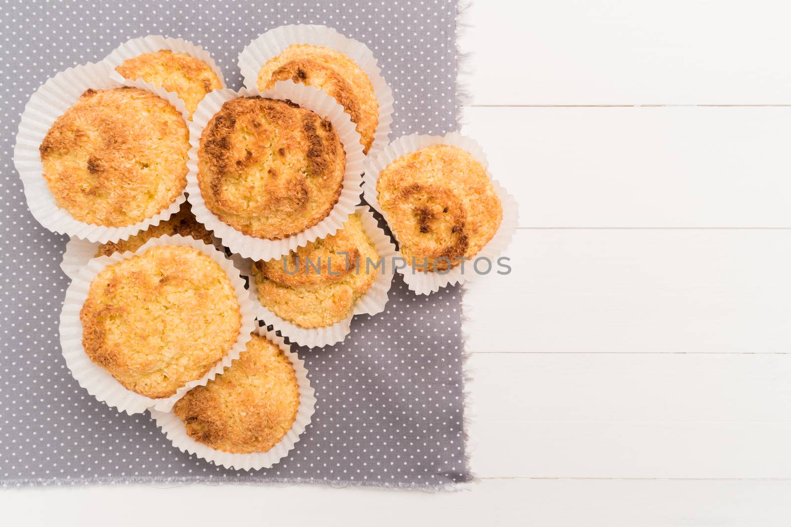 Close up of homemade coconut macaroons, cookie recipe in the oven on rustic wooden background. Top view with copy space.