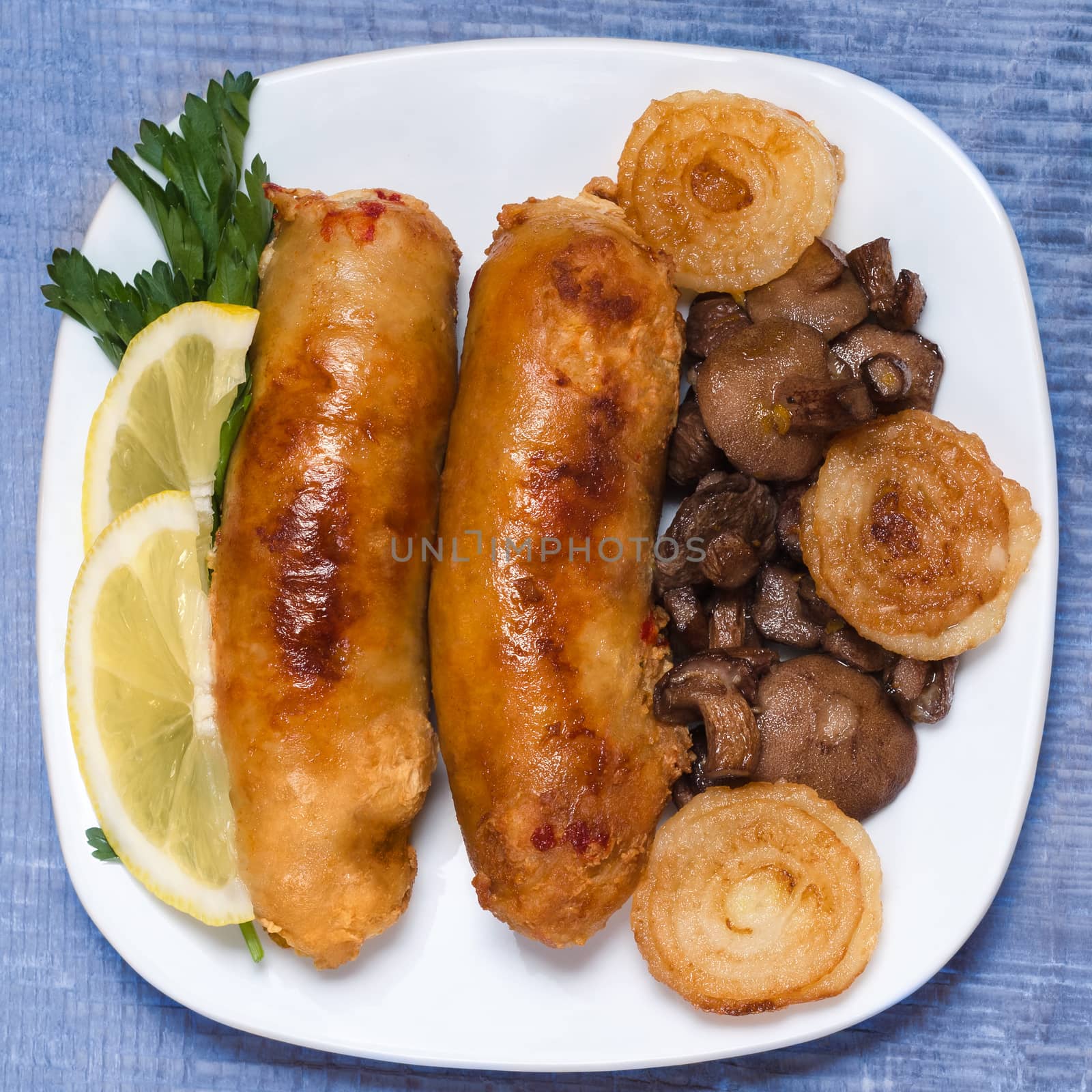 Fried sausage with mushrooms and onions, on wooden background toned with blue.