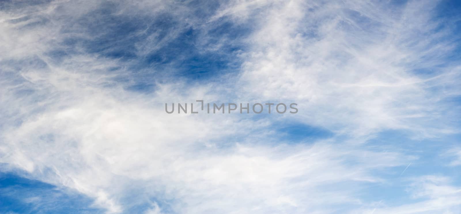 Blue sky, clouds and small condensation trail of airplane at the right side, panorama background