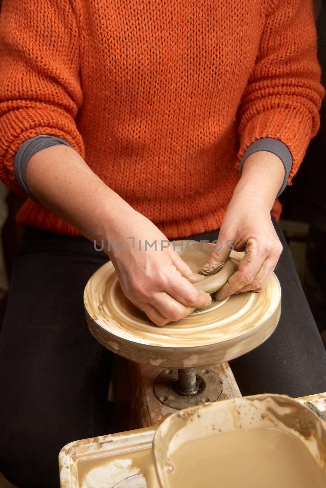 Female hands forming clay pot on the pottery wheel