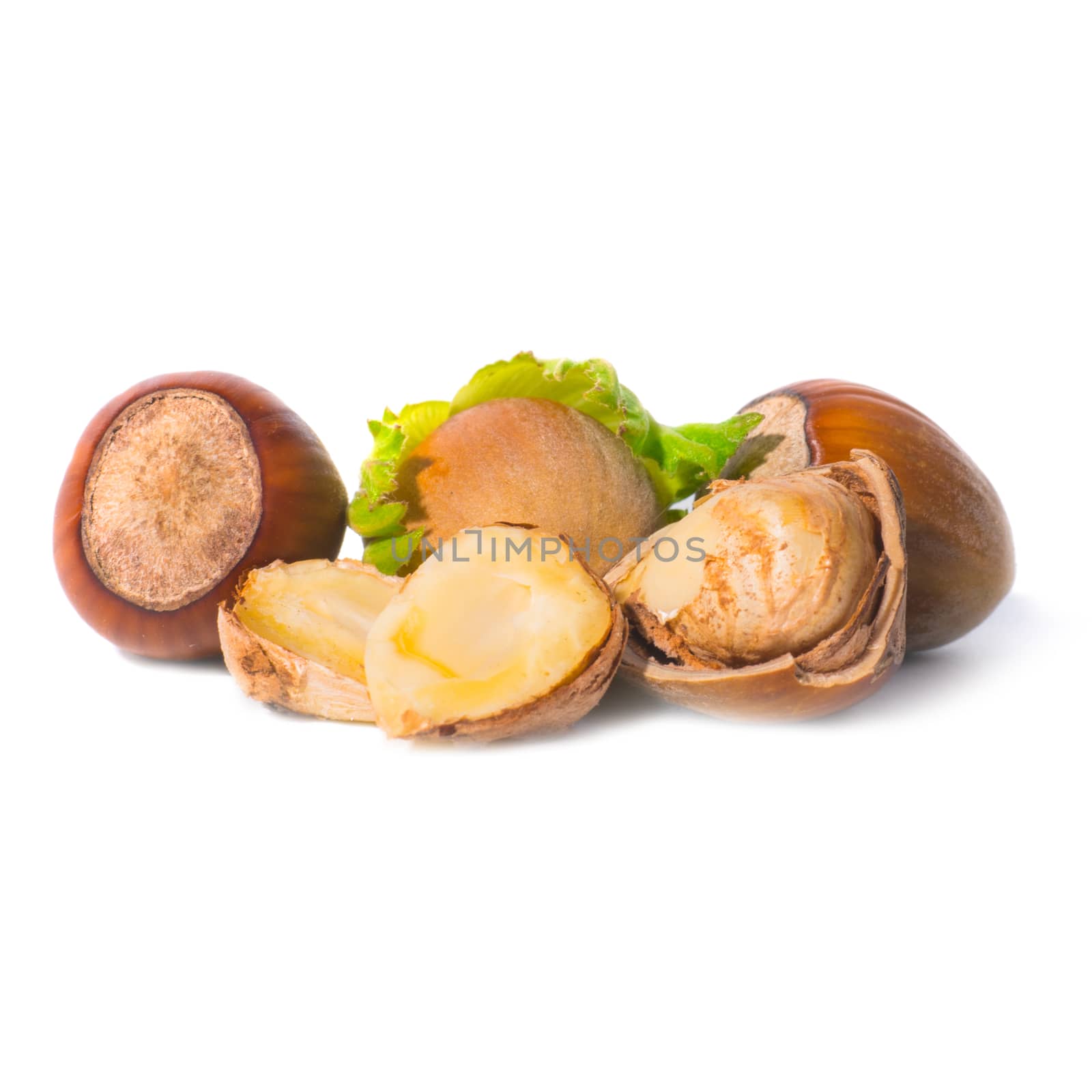 Pile of filbert nuts with green leaf isolated on white