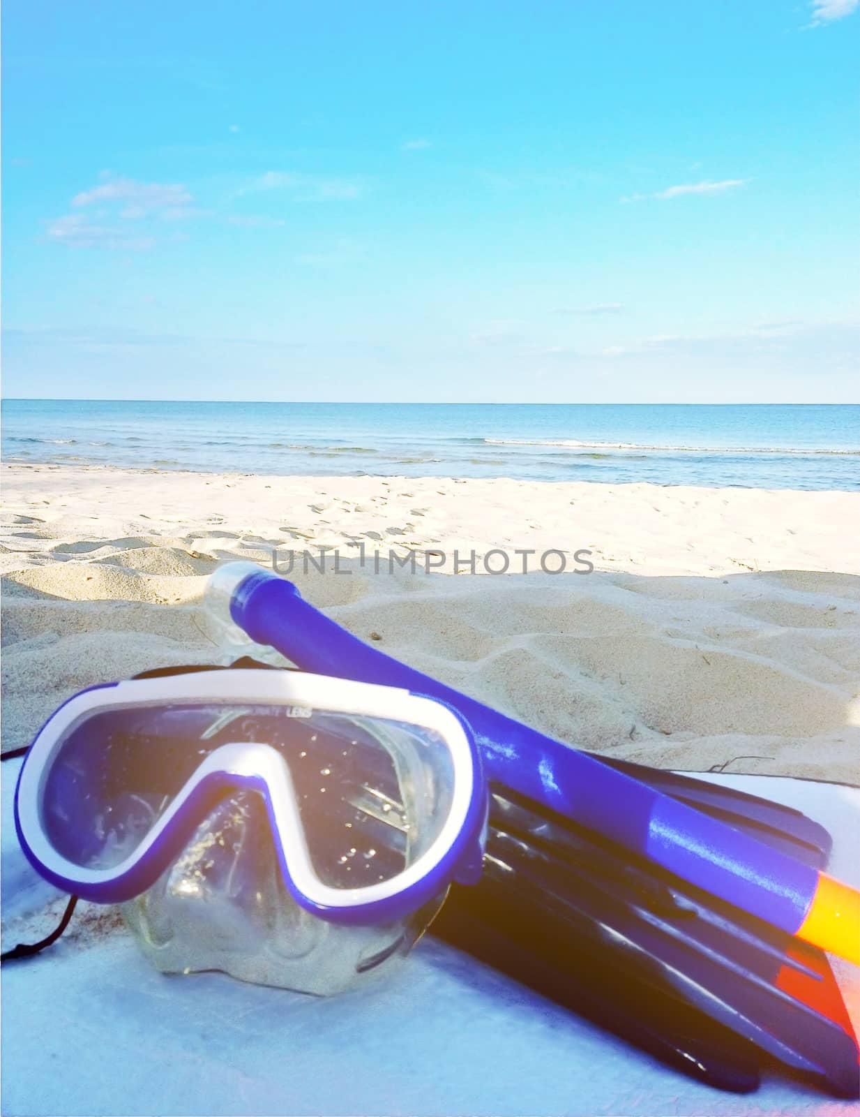 Diving goggles,snorkel on sand beach with sunlight