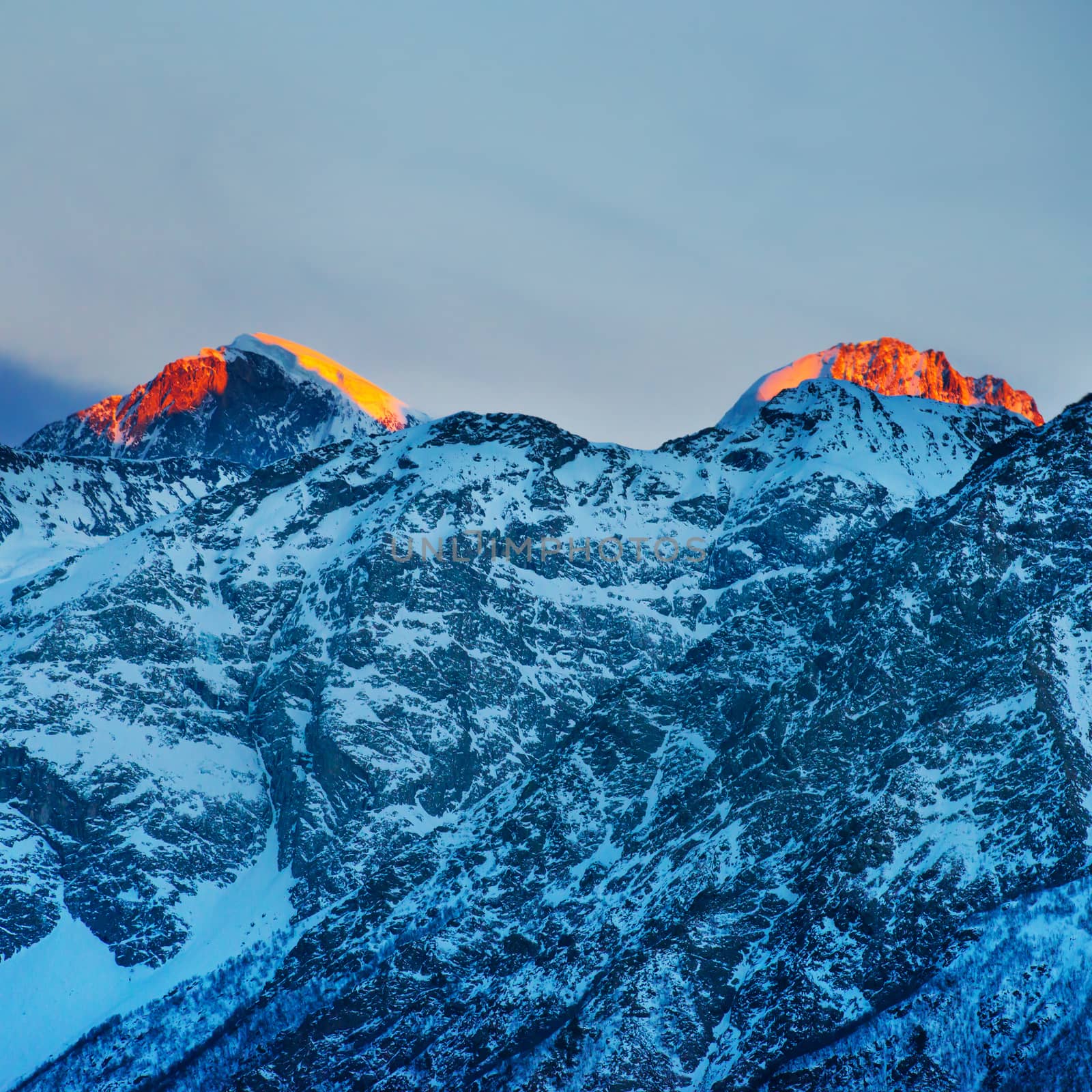 Red sunset in mountains covered by snow.