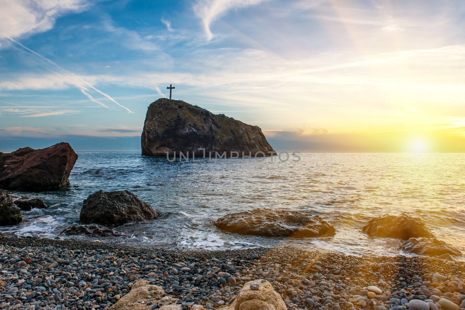 Sunset on the beach with sea, rocks and dramatic sky