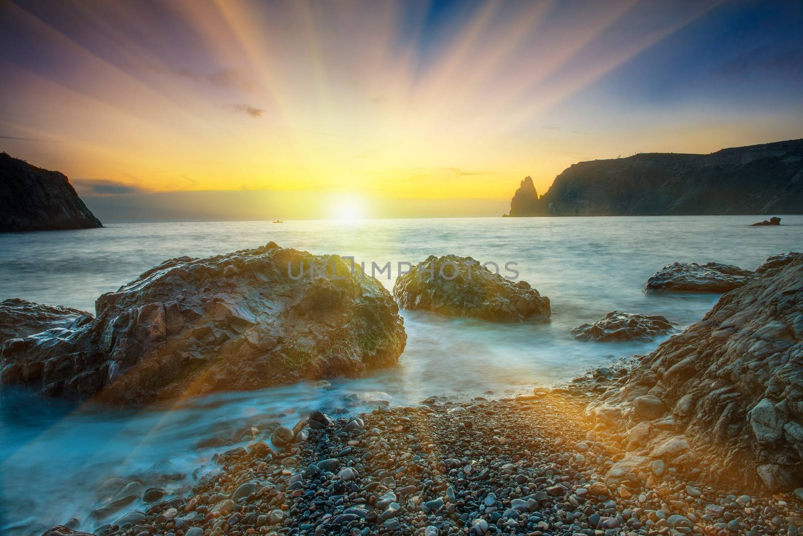 Sunset on the beach with sea, rocks and dramatic sky