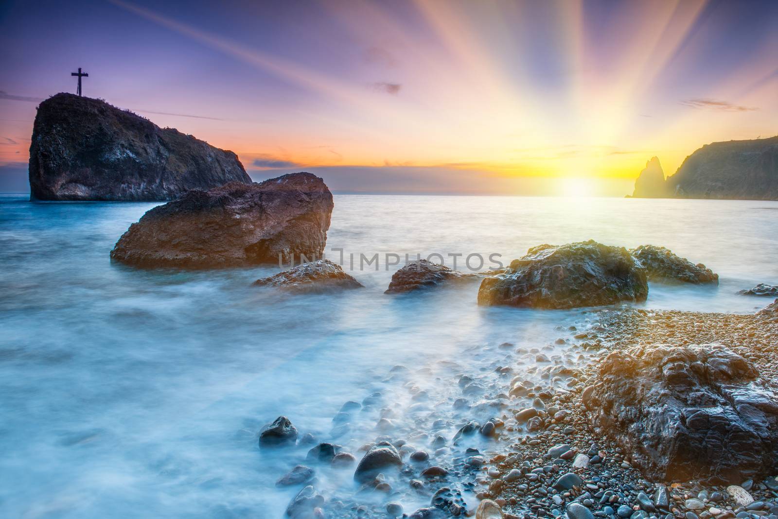 Sunset on the beach with sea, rocks and dramatic sky. Seaside landscape