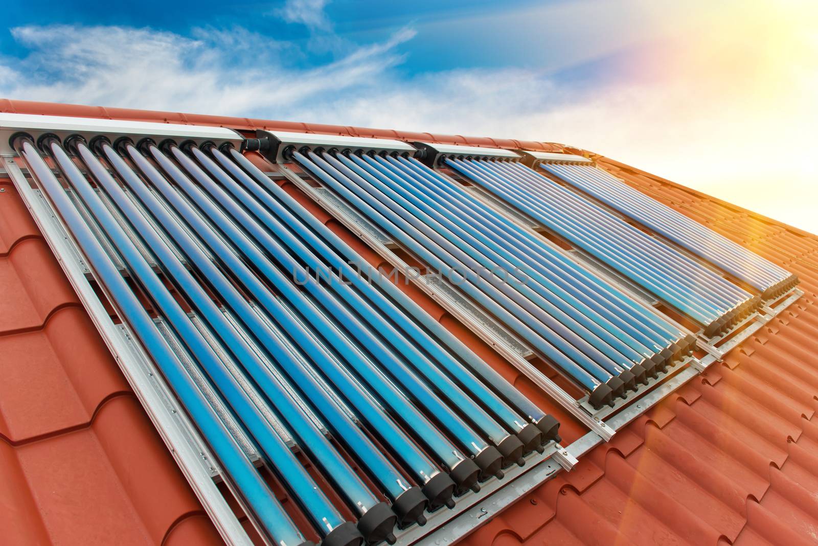 Vacuum collectors- solar water heating system on red roof of the house.