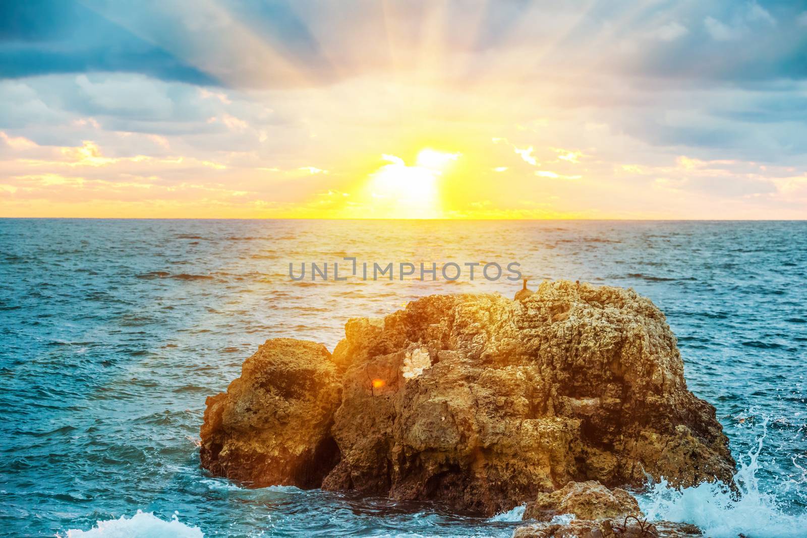 Sunset on the beach with waves, sea, rocks and dramatic sky