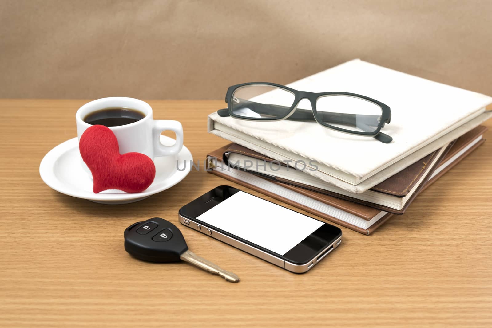 office desk : coffee and phone with car key,eyeglasses,stack of book,heart