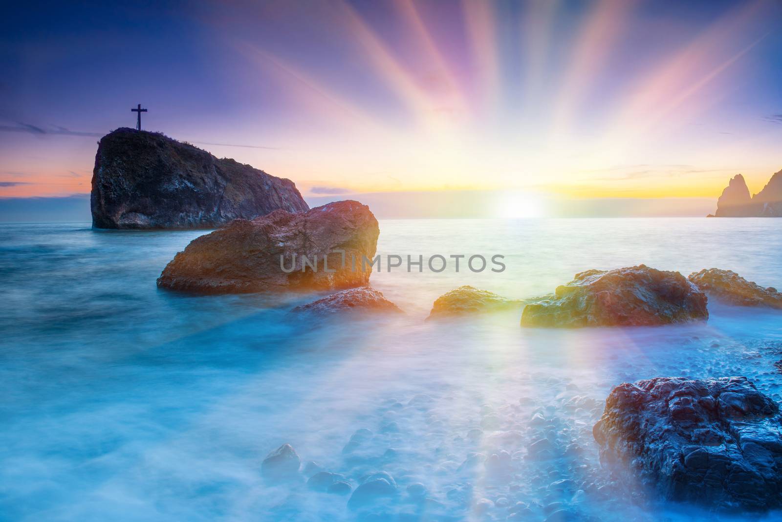 Sunset on the beach with sea, rocks and dramatic sky