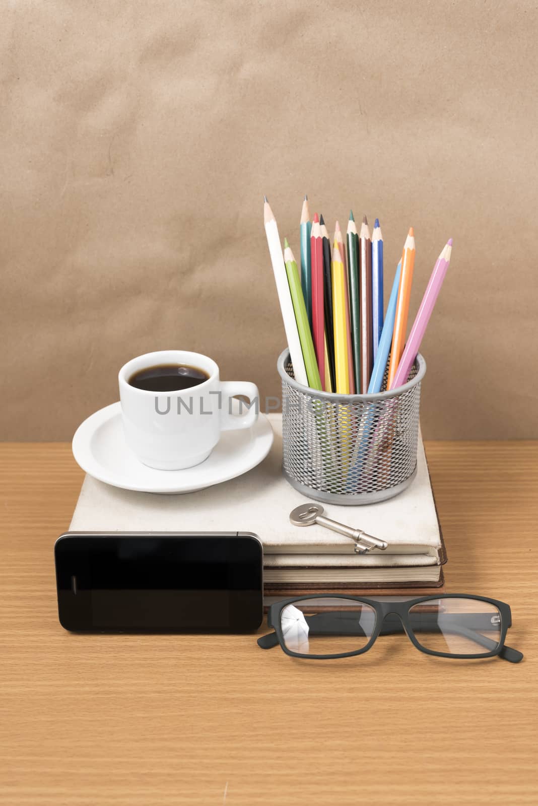 office desk : coffee and phone with key,eyeglasses,stack of book,pencil box