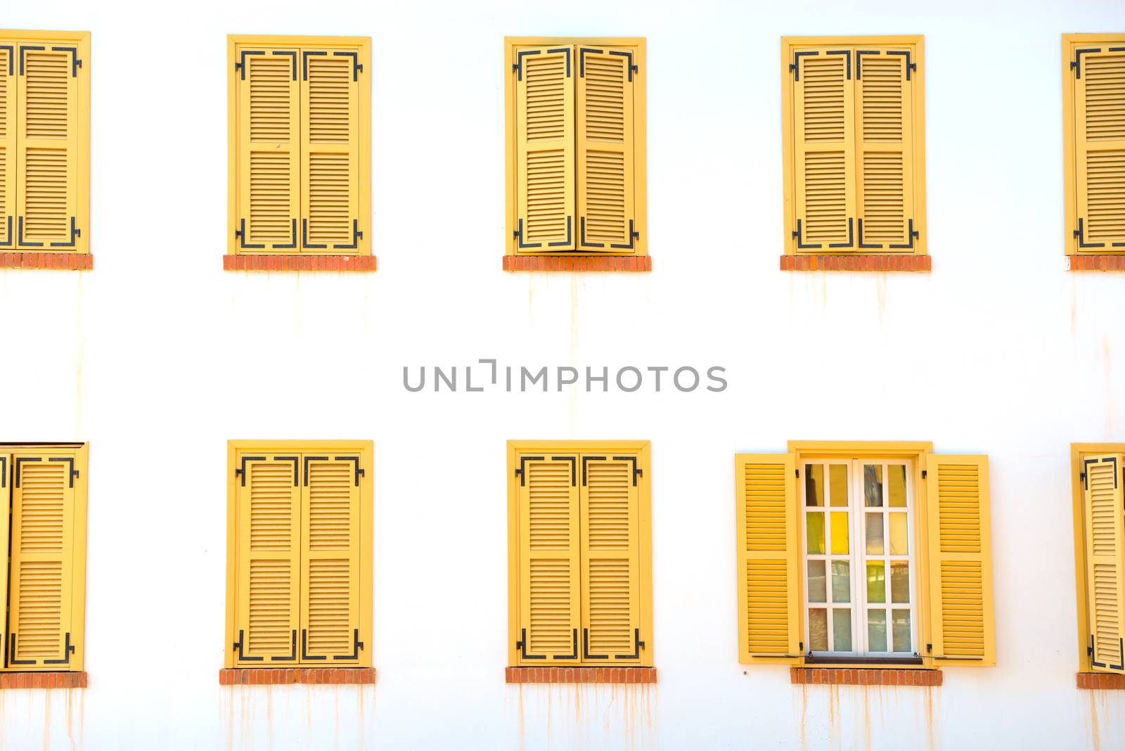 Many closed windows with shutters on the white wall